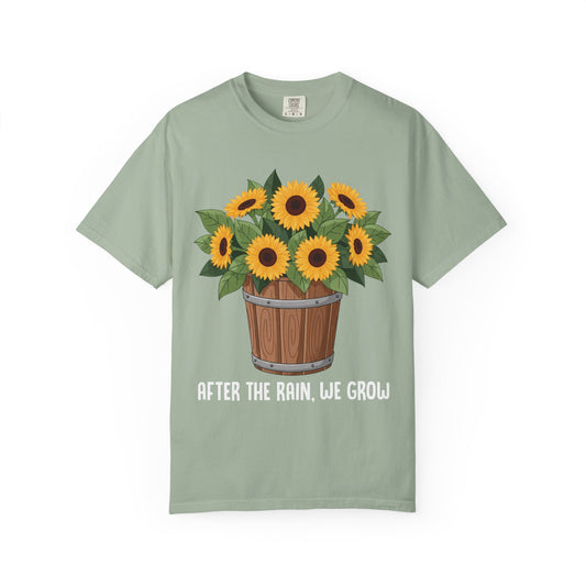 Bucket of sunflowers with After the Rain, We Grow underneath, on a bay green shirt
