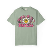 Mental Health Matters with a smiling daisy and pink checkerboard, on a bay green shirt