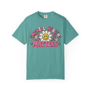 Mental Health Matters with a smiling daisy and pink checkerboard, on a seafoam shirt